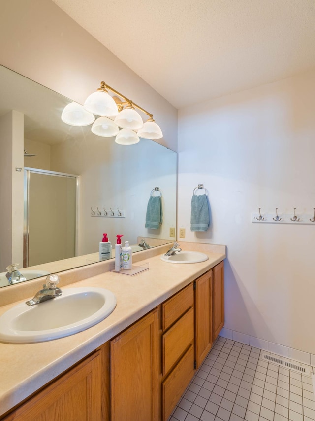 bathroom featuring a sink, a shower stall, double vanity, and tile patterned flooring