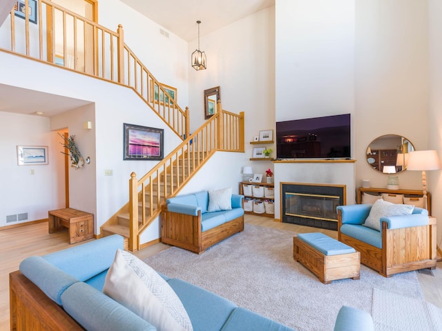 living room with stairway, visible vents, wood finished floors, and a towering ceiling