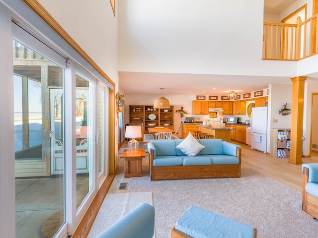 living area featuring a high ceiling, visible vents, and light wood finished floors