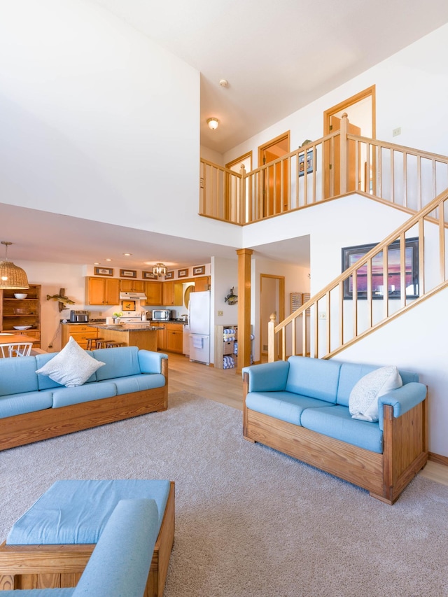 living room featuring light colored carpet, stairs, and a towering ceiling