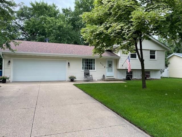 tri-level home featuring an attached garage, concrete driveway, and a front lawn