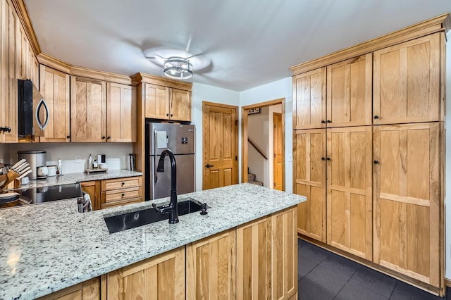 kitchen featuring dark tile patterned floors, a sink, light stone counters, a peninsula, and appliances with stainless steel finishes