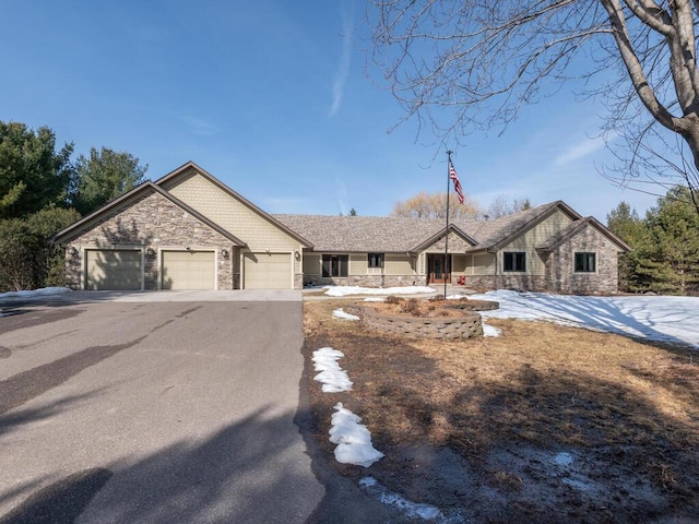 view of front of house featuring aphalt driveway, stone siding, and an attached garage