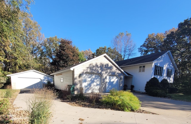 view of side of property featuring an outbuilding, an attached garage, and driveway