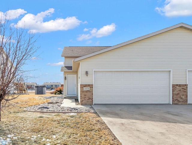 view of front of home featuring concrete driveway, an attached garage, brick siding, and roof with shingles