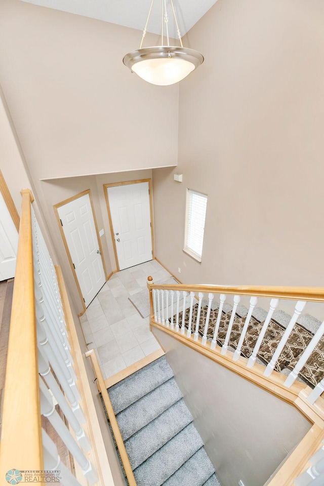 staircase with baseboards and a towering ceiling