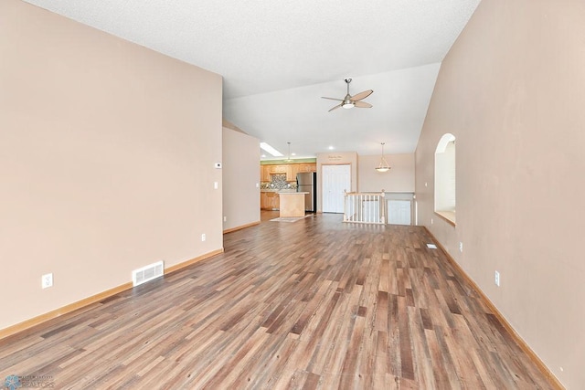 unfurnished living room featuring visible vents, baseboards, lofted ceiling, light wood-style floors, and a ceiling fan