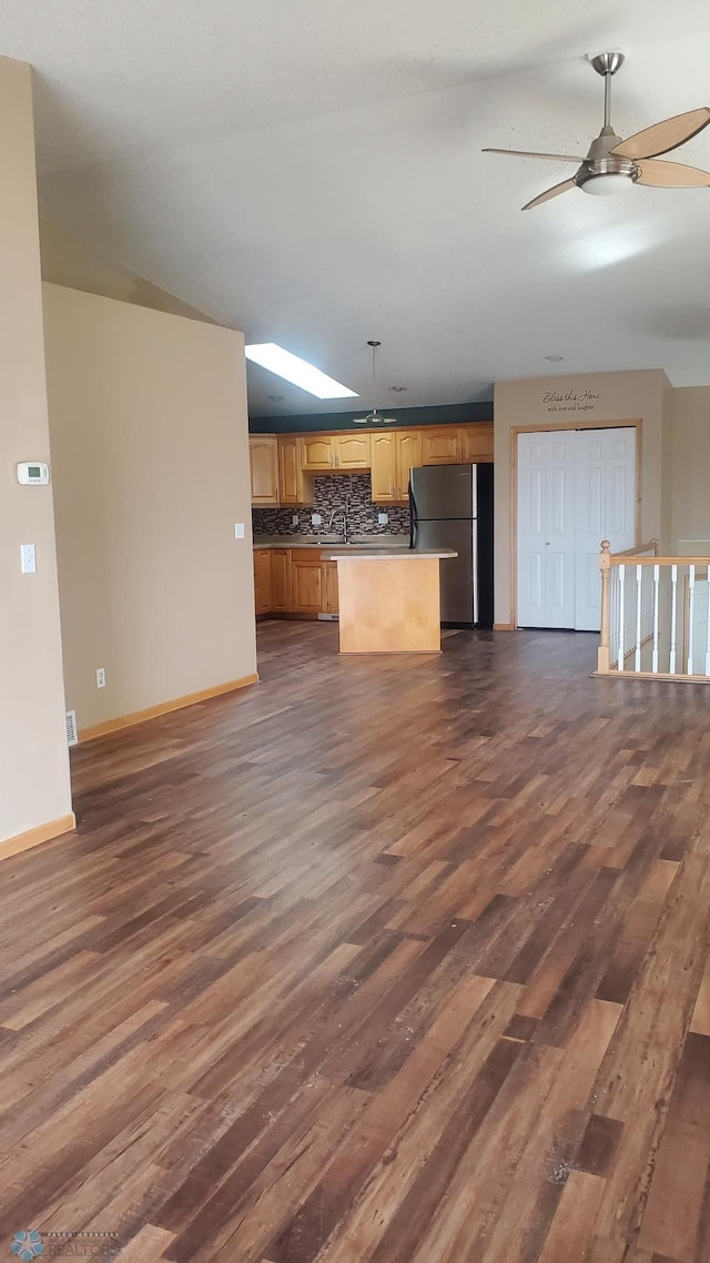 unfurnished living room featuring dark wood finished floors, baseboards, a ceiling fan, and a sink