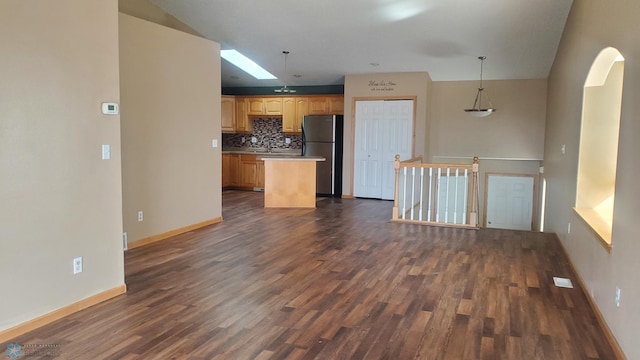 kitchen with tasteful backsplash, a center island, dark wood finished floors, freestanding refrigerator, and arched walkways