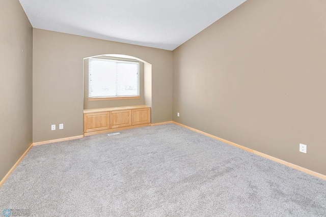 carpeted empty room featuring baseboards