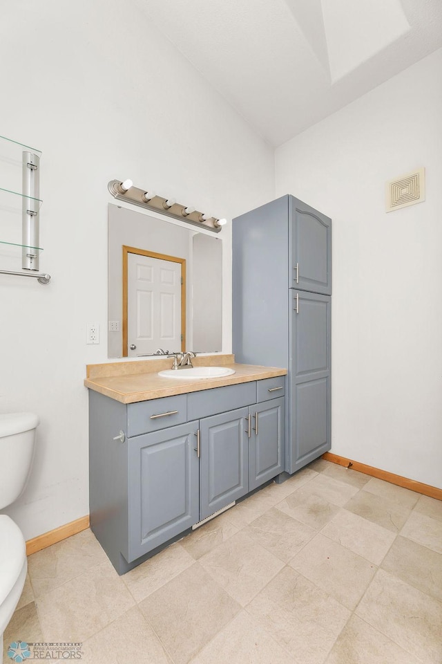 bathroom featuring vanity, toilet, visible vents, and baseboards