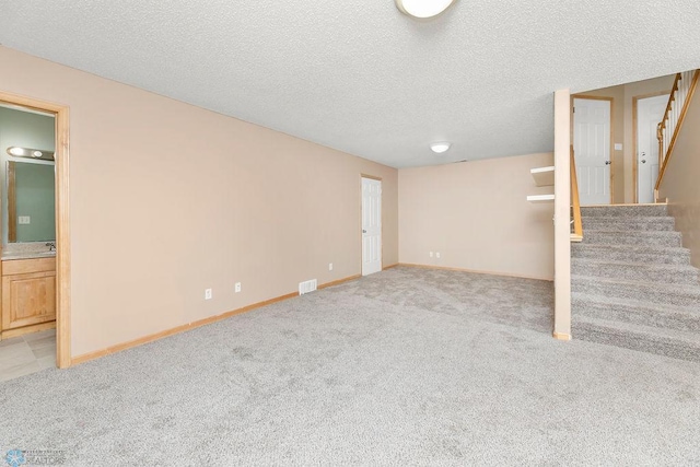 finished below grade area featuring stairway, baseboards, visible vents, and carpet floors