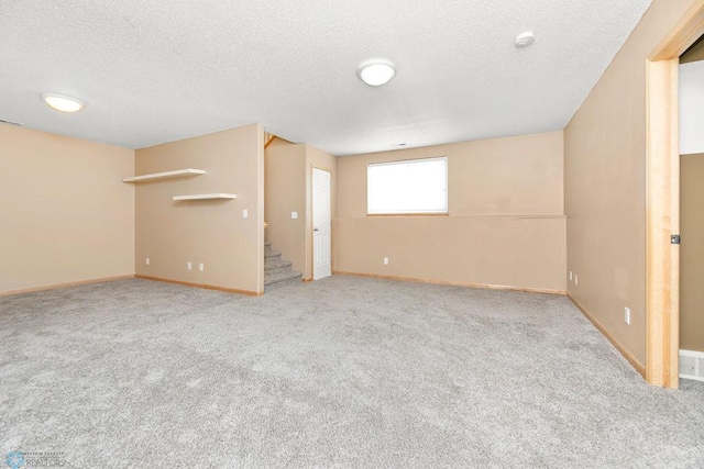 basement featuring stairway, a textured ceiling, visible vents, and carpet flooring