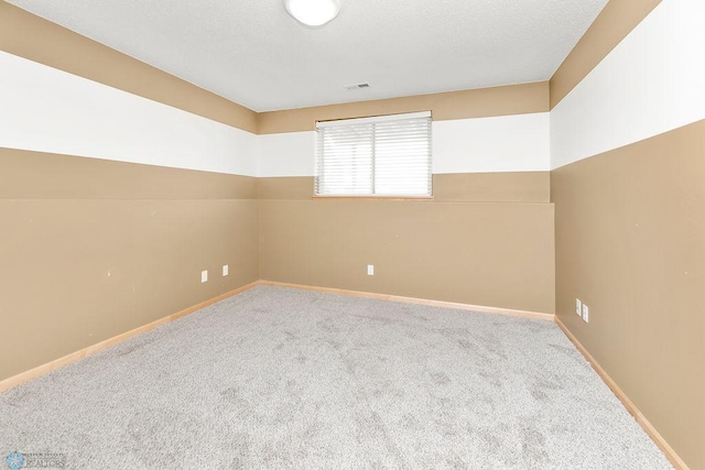 carpeted spare room with visible vents, a textured ceiling, and baseboards