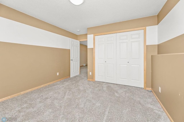 unfurnished bedroom with a closet, a textured ceiling, baseboards, and carpet