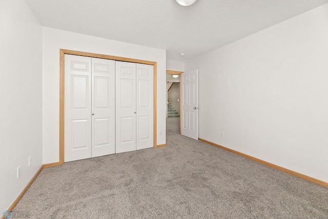 unfurnished bedroom featuring a closet, carpet flooring, a textured ceiling, and baseboards