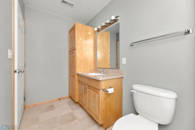 bathroom with vanity, baseboards, visible vents, a textured ceiling, and toilet