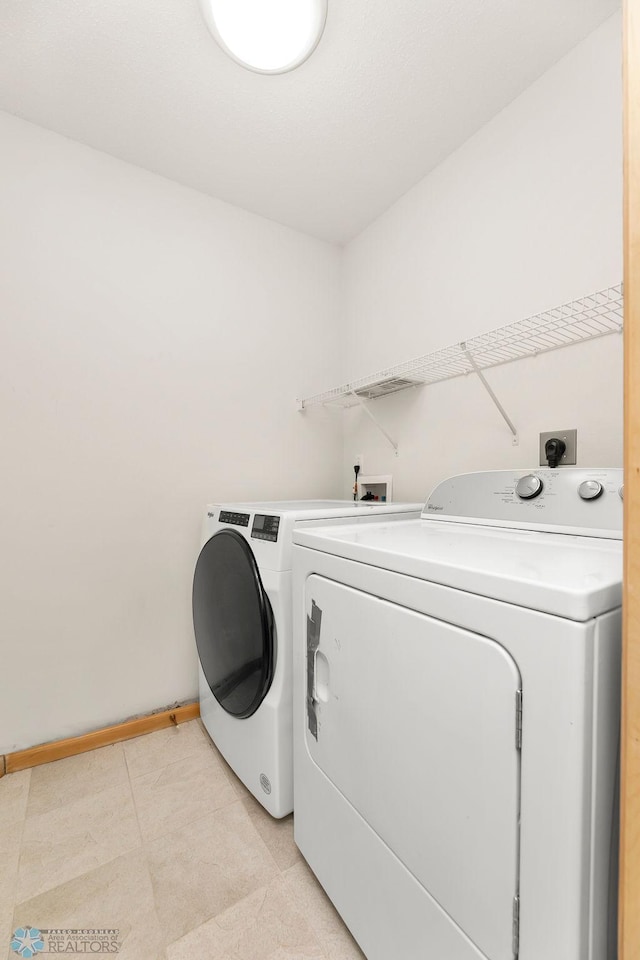 laundry room with laundry area, light tile patterned flooring, baseboards, and independent washer and dryer