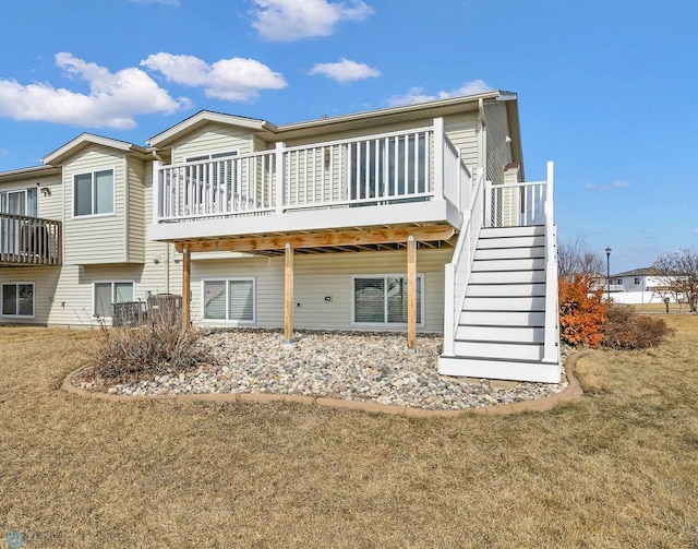 rear view of property featuring stairs, a yard, and a wooden deck