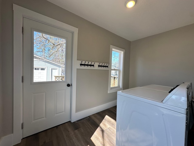 clothes washing area with dark wood finished floors, laundry area, washer and dryer, and baseboards