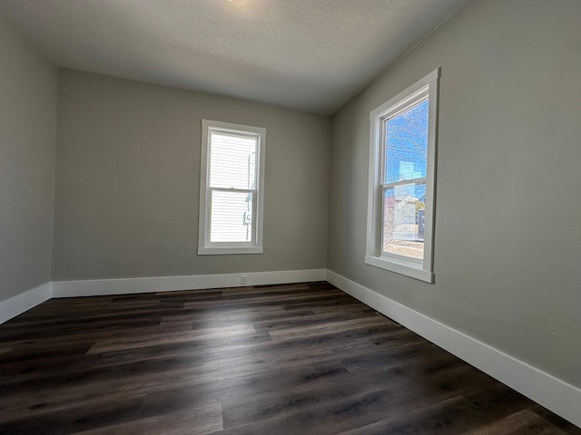 empty room featuring dark wood-style floors, baseboards, and a wealth of natural light