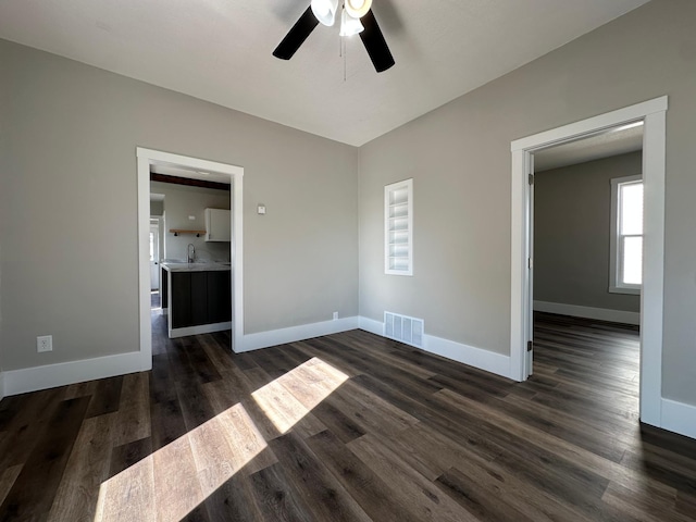 spare room featuring dark wood-style floors, visible vents, baseboards, a sink, and ceiling fan