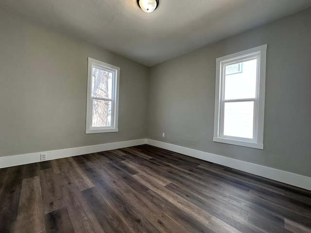 spare room with baseboards and dark wood-style floors