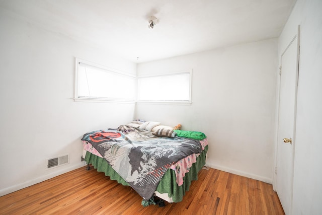 bedroom with visible vents, baseboards, and wood finished floors