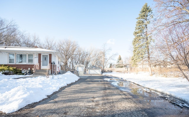 exterior space featuring brick siding, a garage, driveway, and an outdoor structure