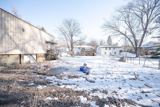 yard layered in snow featuring fence and a residential view