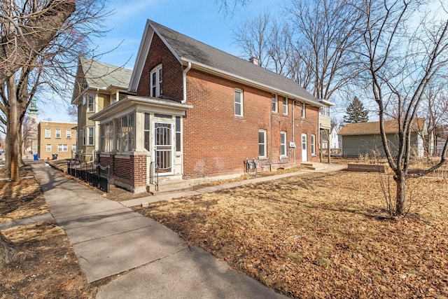 view of property exterior with brick siding, a chimney, and a sunroom