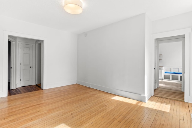 unfurnished room featuring baseboards and light wood-style floors