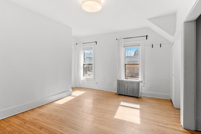 unfurnished room featuring radiator, baseboards, and hardwood / wood-style floors