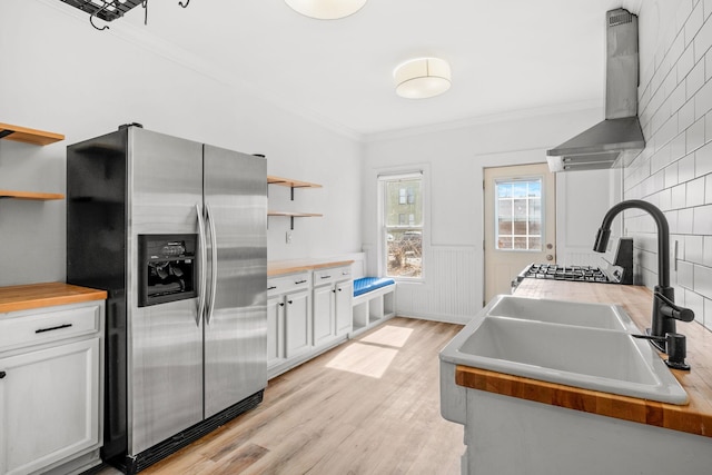 kitchen featuring ornamental molding, light wood-style floors, stainless steel fridge, wall chimney exhaust hood, and open shelves