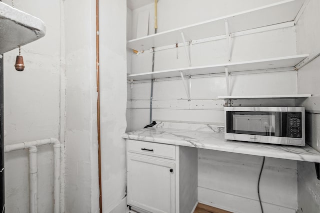 interior space featuring light stone counters, stainless steel microwave, white cabinetry, and open shelves