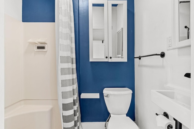 bathroom featuring toilet, a shower with shower curtain, and a sink