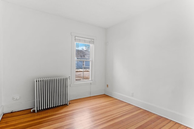 empty room with radiator, baseboards, and wood-type flooring