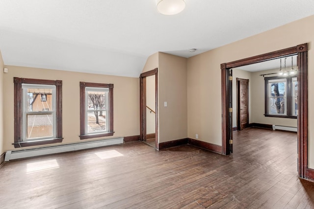 spare room with a baseboard radiator, wood-type flooring, and a healthy amount of sunlight