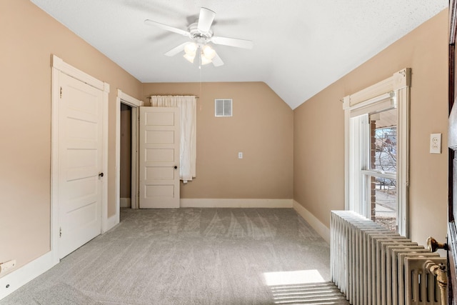 additional living space with carpet, visible vents, baseboards, ceiling fan, and vaulted ceiling