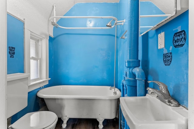 bathroom featuring a sink, a freestanding bath, wood finished floors, and toilet