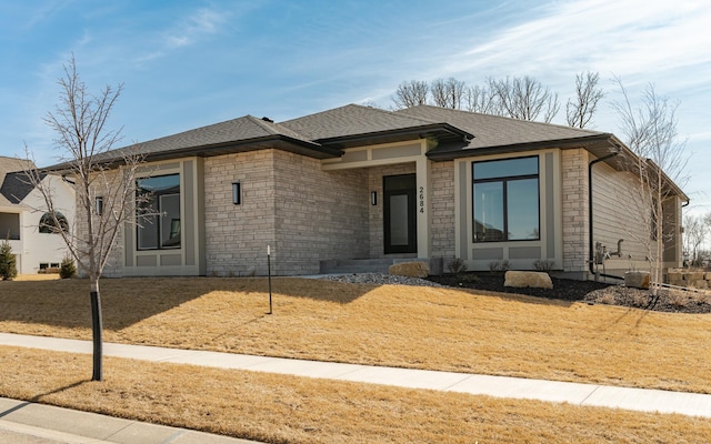 view of front facade featuring stone siding and roof with shingles