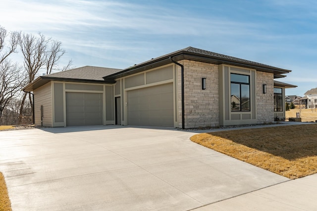 view of front facade featuring an attached garage, stone siding, driveway, and a shingled roof