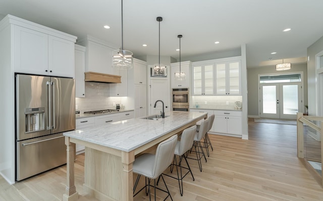 kitchen featuring a breakfast bar, a sink, stainless steel appliances, french doors, and white cabinets