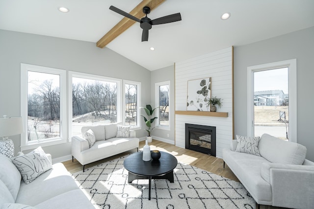 living area with baseboards, vaulted ceiling with beams, recessed lighting, light wood-type flooring, and a large fireplace