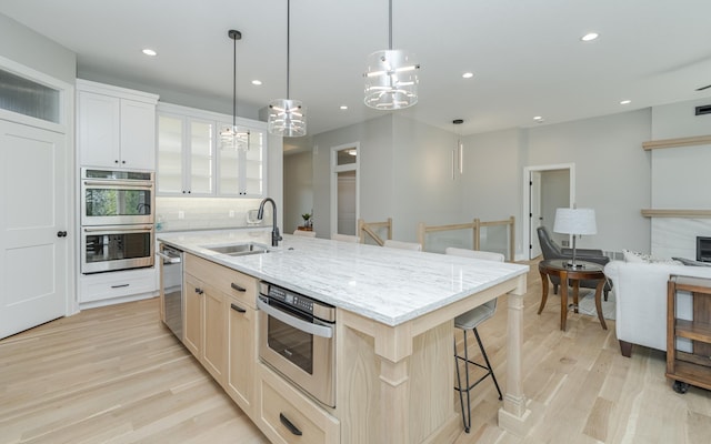 kitchen with a breakfast bar, light wood-style flooring, a sink, double oven, and backsplash