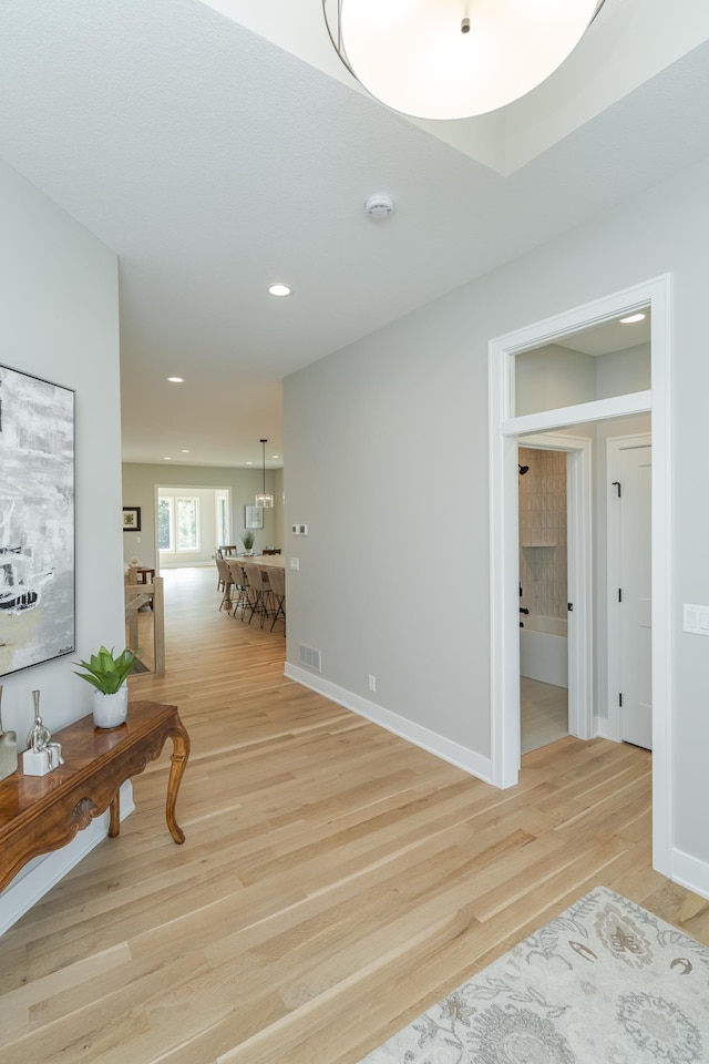 corridor featuring recessed lighting, visible vents, baseboards, and light wood finished floors