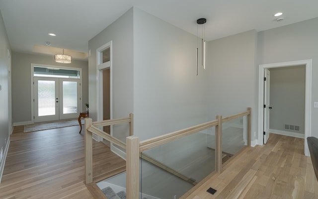 hallway featuring an upstairs landing, visible vents, light wood-style flooring, and french doors