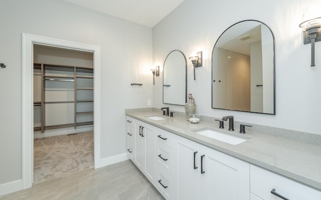 bathroom featuring a sink, visible vents, baseboards, and double vanity