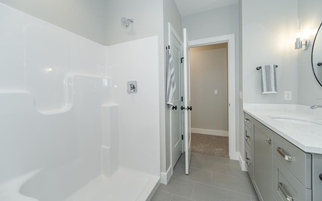 bathroom with baseboards, walk in shower, vanity, and tile patterned flooring