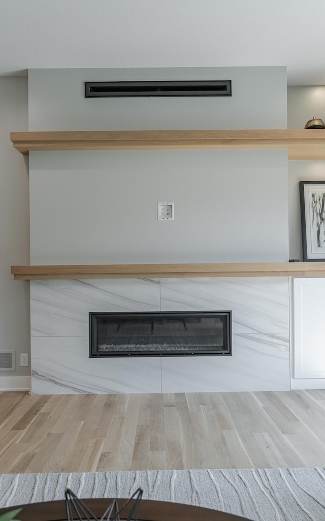 interior details featuring a glass covered fireplace, visible vents, and wood finished floors